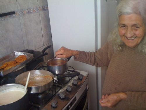 Dona Deza cozinha sorrindo e prepara carne recheada na panela
